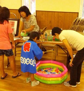 Toshiko-san helps boy in happi fish while Rika-san answers questions